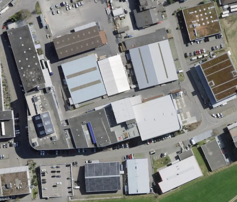 Luftbild eines Gewerbegebiets mit Hallen und Flachdächern, einige mit Solaranlagen